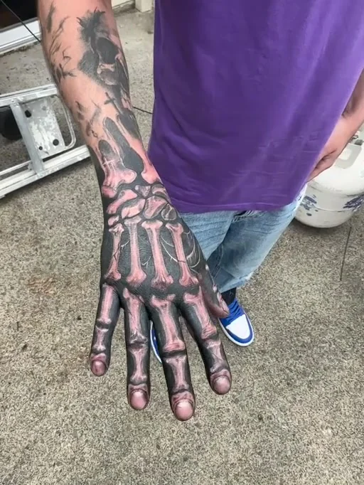 Realistic skeletal bones tattooed along a hand and forearm