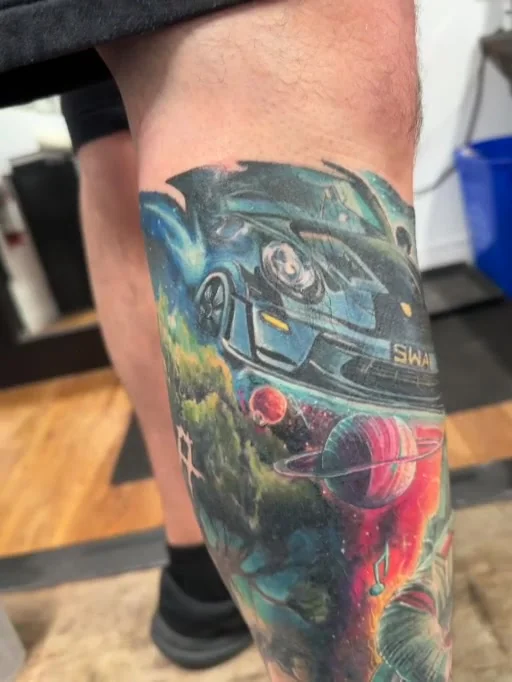 Colour leg tattoo with a sports car and vivid cosmic imagery